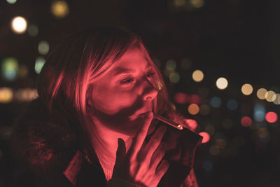 Portrait of a young woman in red backlight smoke a cigarett