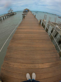 Low section of person on pier at beach against sky