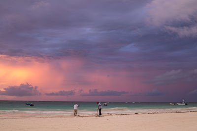 People on beach against sky during sunset