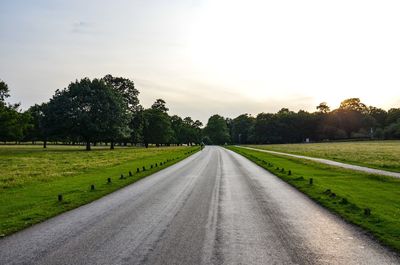 Road amidst field against clear sky