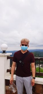 Young man looking at sea against sky