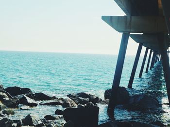 Low section of swimming pool by sea against clear sky