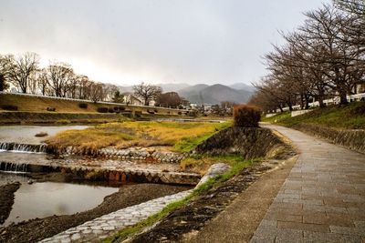 View of footpath by river against sky