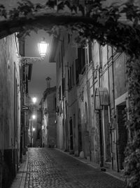 Narrow street amidst buildings in city at night