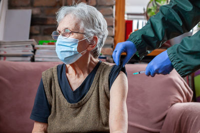 Cropped hand of doctor vaccinating senior woman