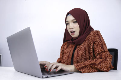 Young woman looking away while sitting on smart phone