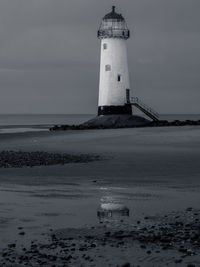 Lighthouse by sea against sky