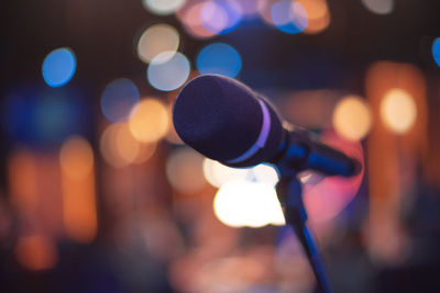Close-up of microphone in illuminated auditorium