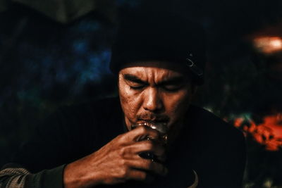 Close-up of man smoking at night