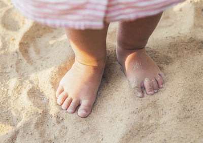 Low section of person on sand at sandy beach