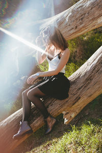 Side view of woman sitting on wood