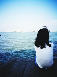 Rear view of woman standing in sea against clear sky