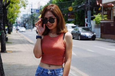 Young woman wearing sunglasses while standing on road