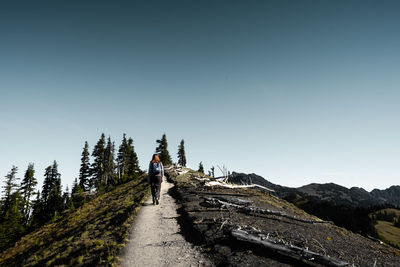 Rear view of man walking on mountain against sky