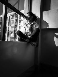 Young woman looking through window at home