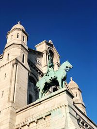 Low angle view of statue of building against blue sky