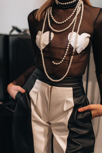Figure of fashion model wearing top with hearts, black and white pants with zipper and pearl beads