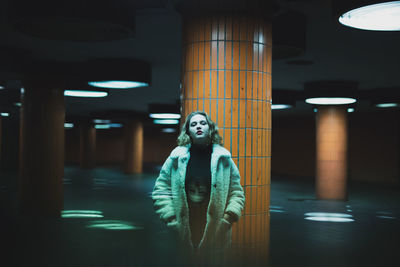 Portrait of woman standing in illuminated garage