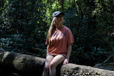 Young woman standing on rock against trees