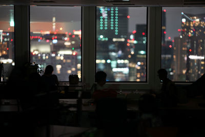 Silhouette people at illuminated office building at night