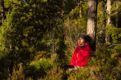 Woman with eyes closed by tree at forest