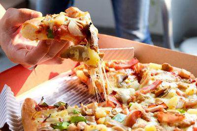 Close-up of hand holding pizza on table