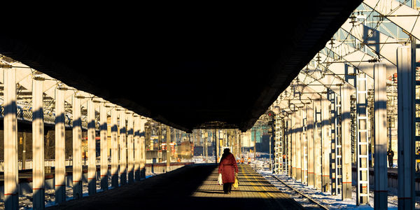 Silhouette woman with bags walking on railroad station platform