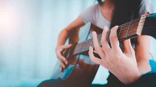 Midsection of woman playing guitar