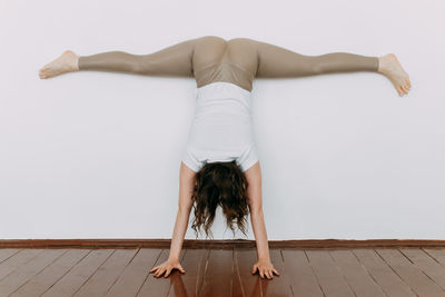 Rear view of woman relaxing on floor against wall