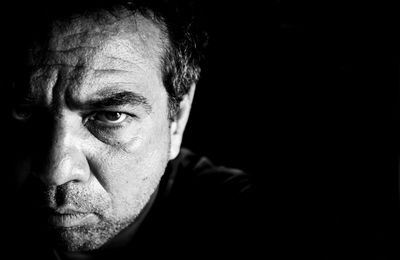 Portrait of angry man against black background