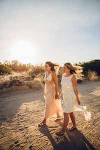 Full length of happy friends on beach against sky