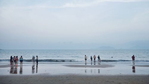 People at beach against sky