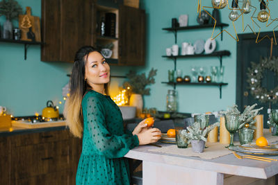 Lovely woman holds tangerines in her hands in a kitchen decorated for christmas person