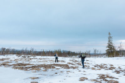 Men walking on snow field against sky
