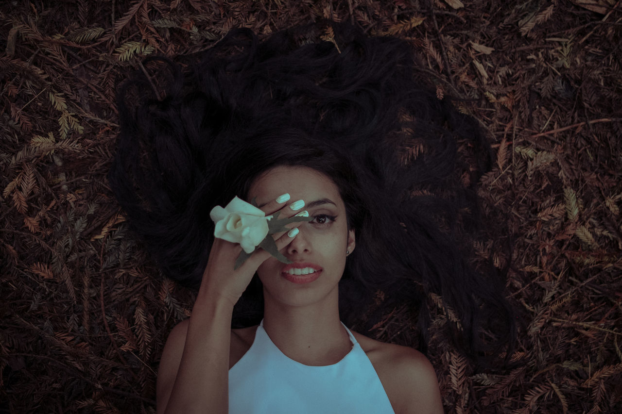 one person, front view, real people, young women, young adult, beautiful woman, headshot, portrait, lifestyles, long hair, looking at camera, leisure activity, plant, outdoors, close-up, leaf, flower, nature, day, beauty, human hand, freshness, people