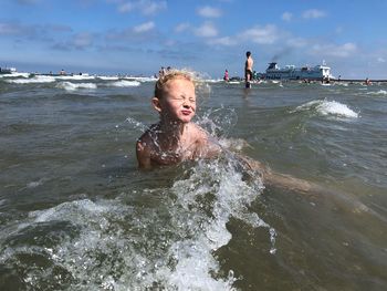 Boy enjoying on beach against sky