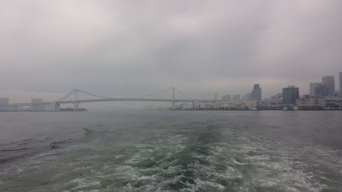 City at waterfront against cloudy sky