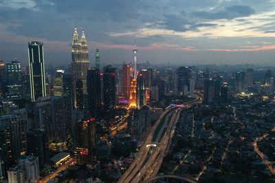 Aerial view of illuminated buildings in city against sky