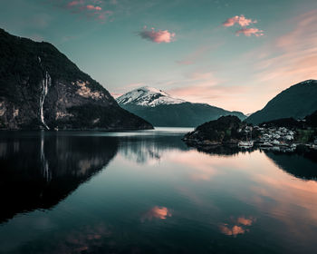 Scenic view of lake by mountains against sky during sunset