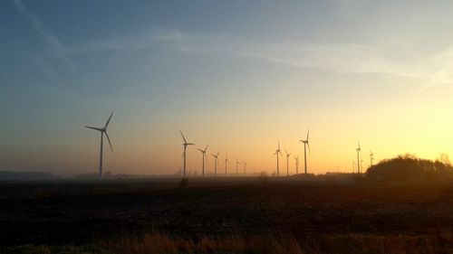 Wind turbines on field at sunset