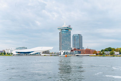 View of buildings in city against cloudy sky