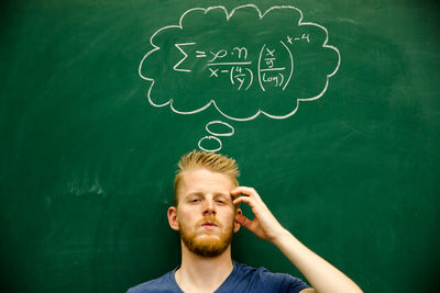 Man gesturing with mathematical formula on blackboard