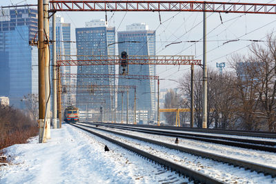 Urban winter landscape with a view of a multiline railway line with a moving electric train on  day.