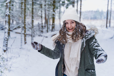 Young woman standing on snow covered tree