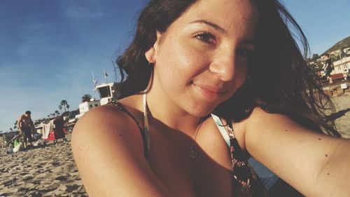 Portrait of smiling young woman on beach against sky