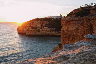 Rock formation on sea against sky during sunset