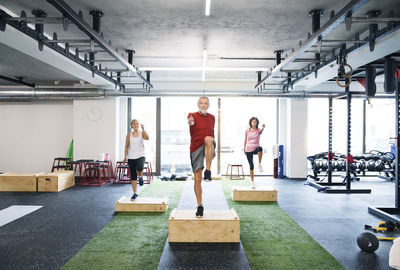 Group of fit seniors working out with wooden boxes in gym