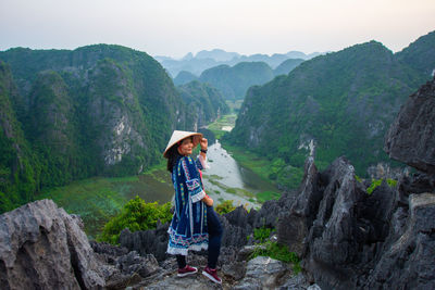 Full length of woman standing on mountain against sky