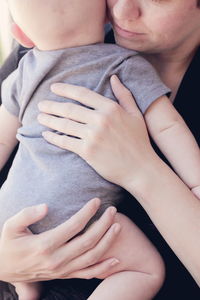 Midsection of mother carrying son while standing at home