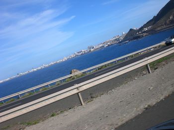 Road by sea against blue sky